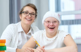 Portrait of happy mother and girl with Down Syndrome at home